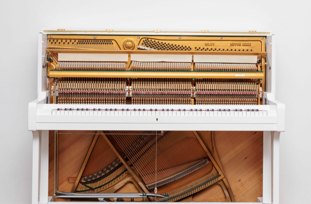 Piano droit blanc ouvert, vue du mécanisme interne